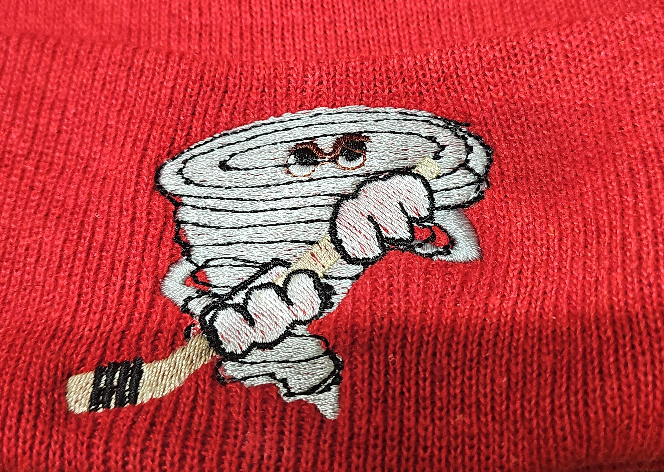 Tornado mascot holding a hockey stick embroidered on a red beanie