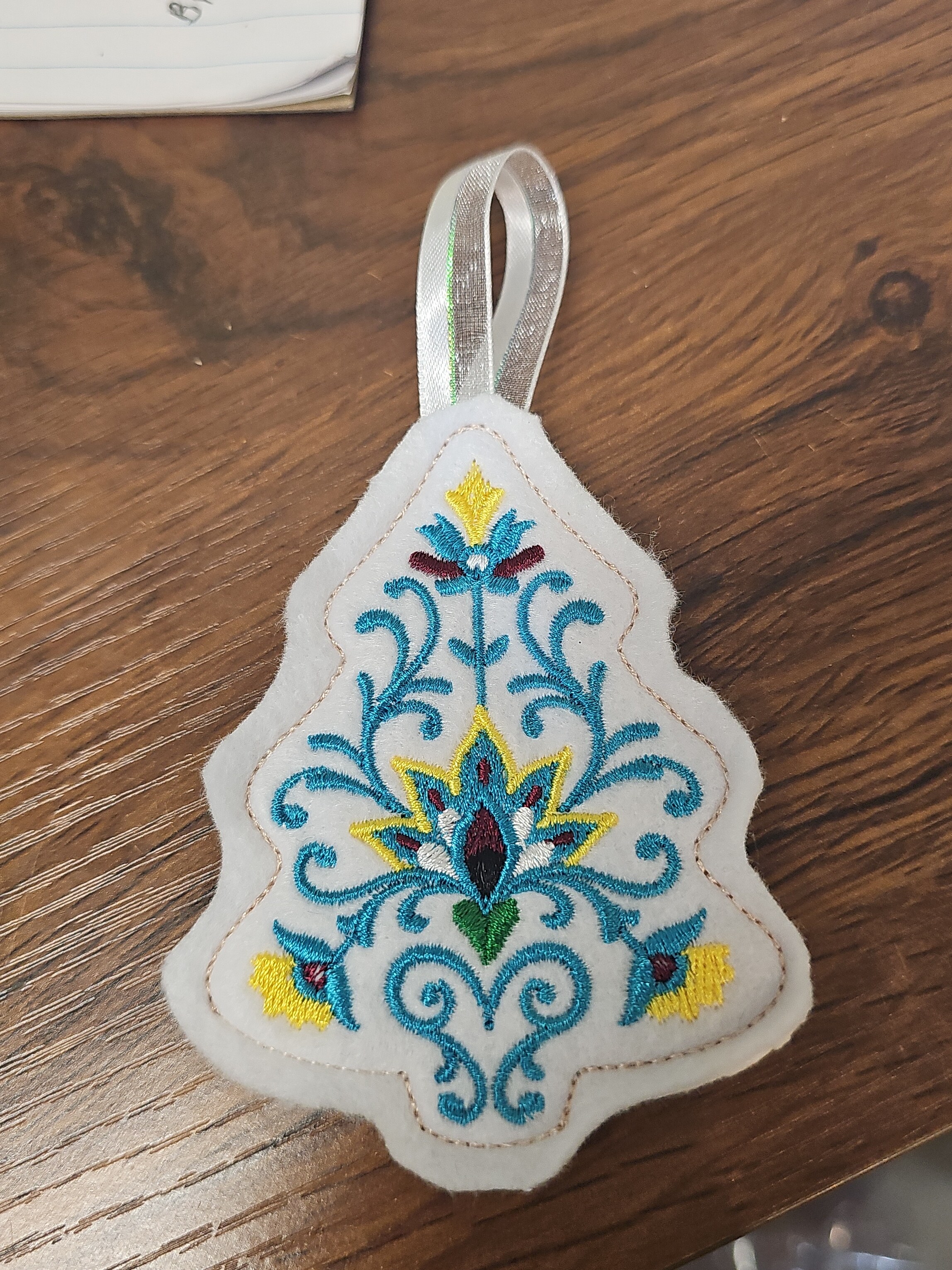 Embroidered Christmas tree ornament with colorful floral stitching
