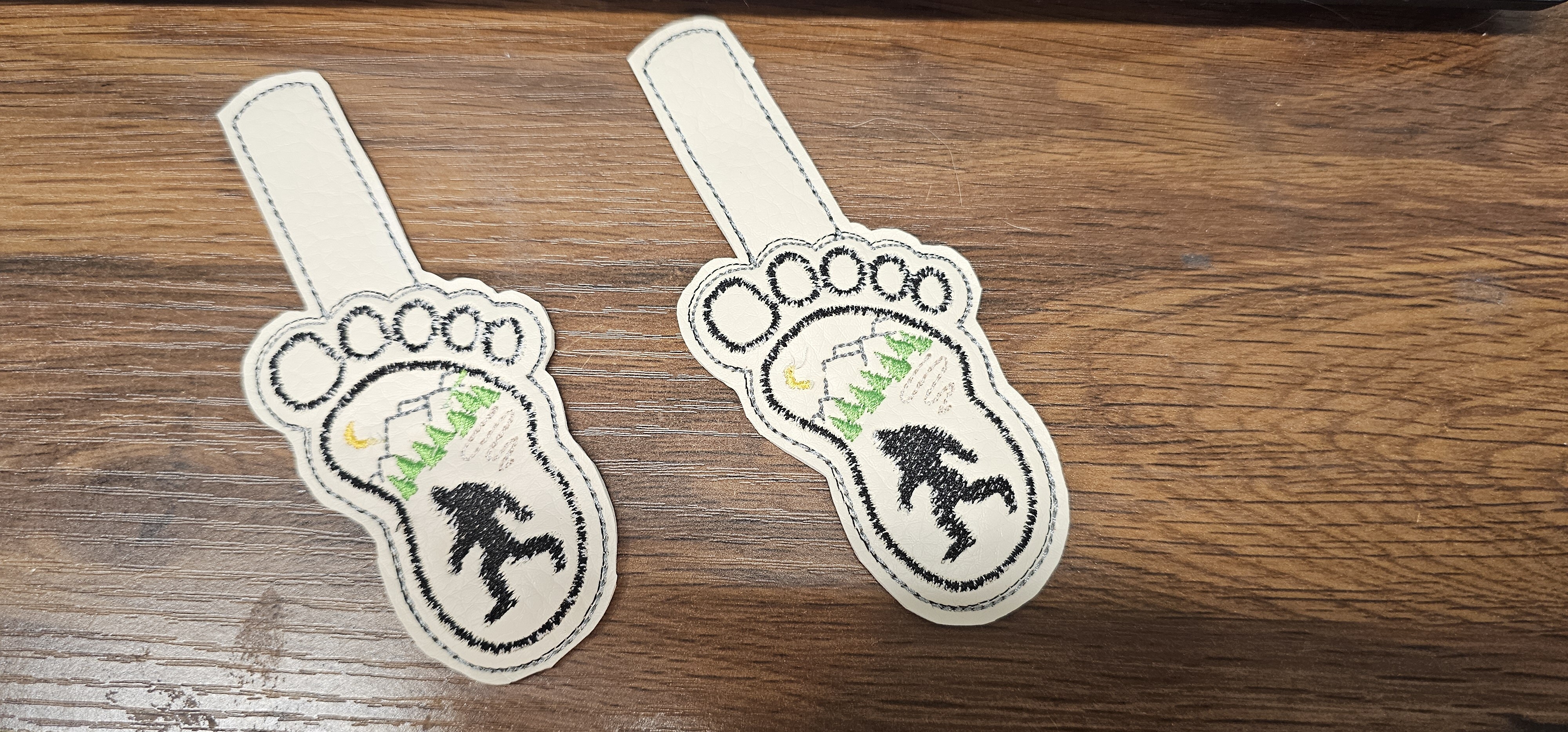 Pair of embroidered footprint key fobs with a forest and animal design