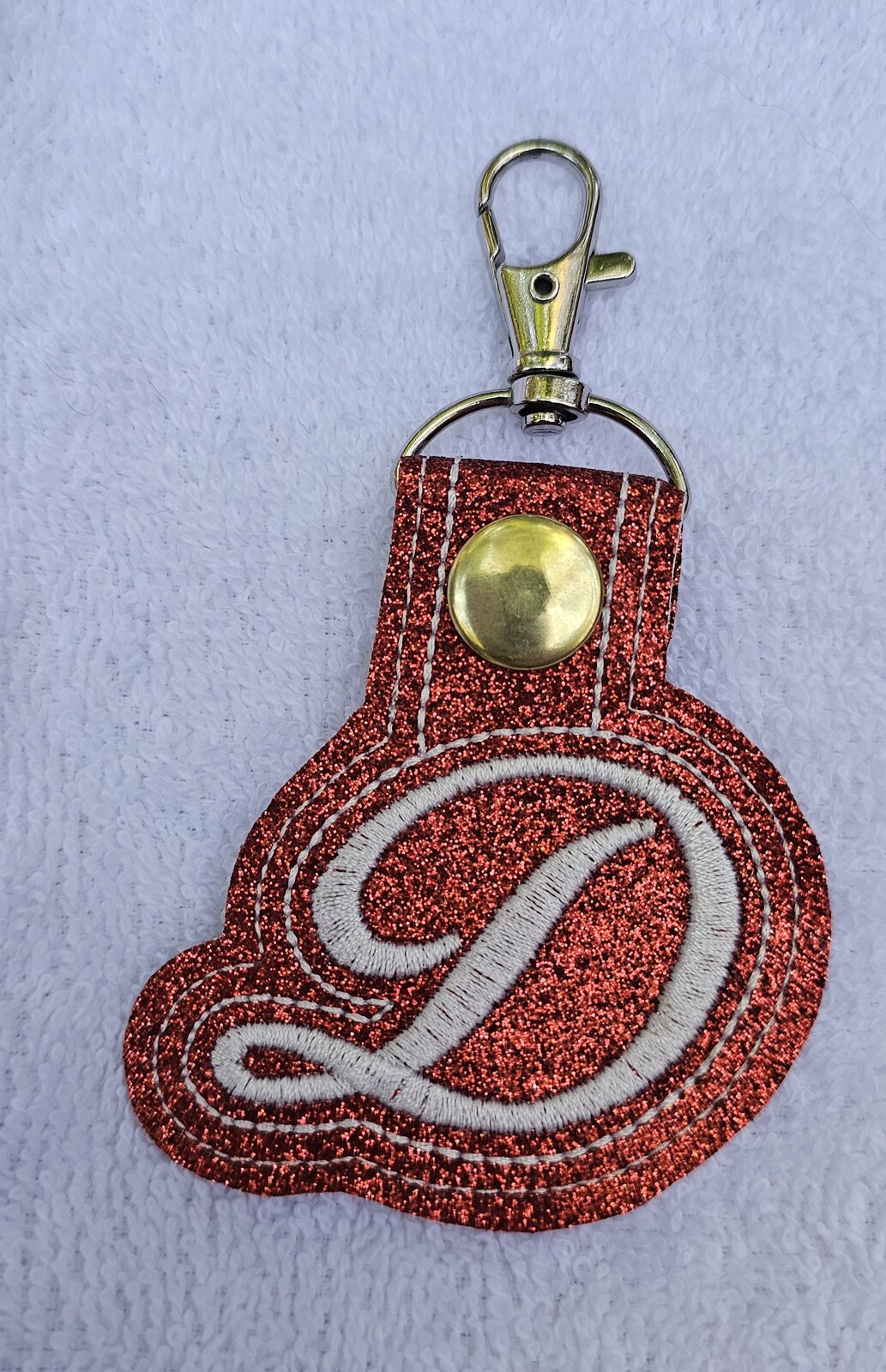 Red glitter key fob embroidered with a white script letter D