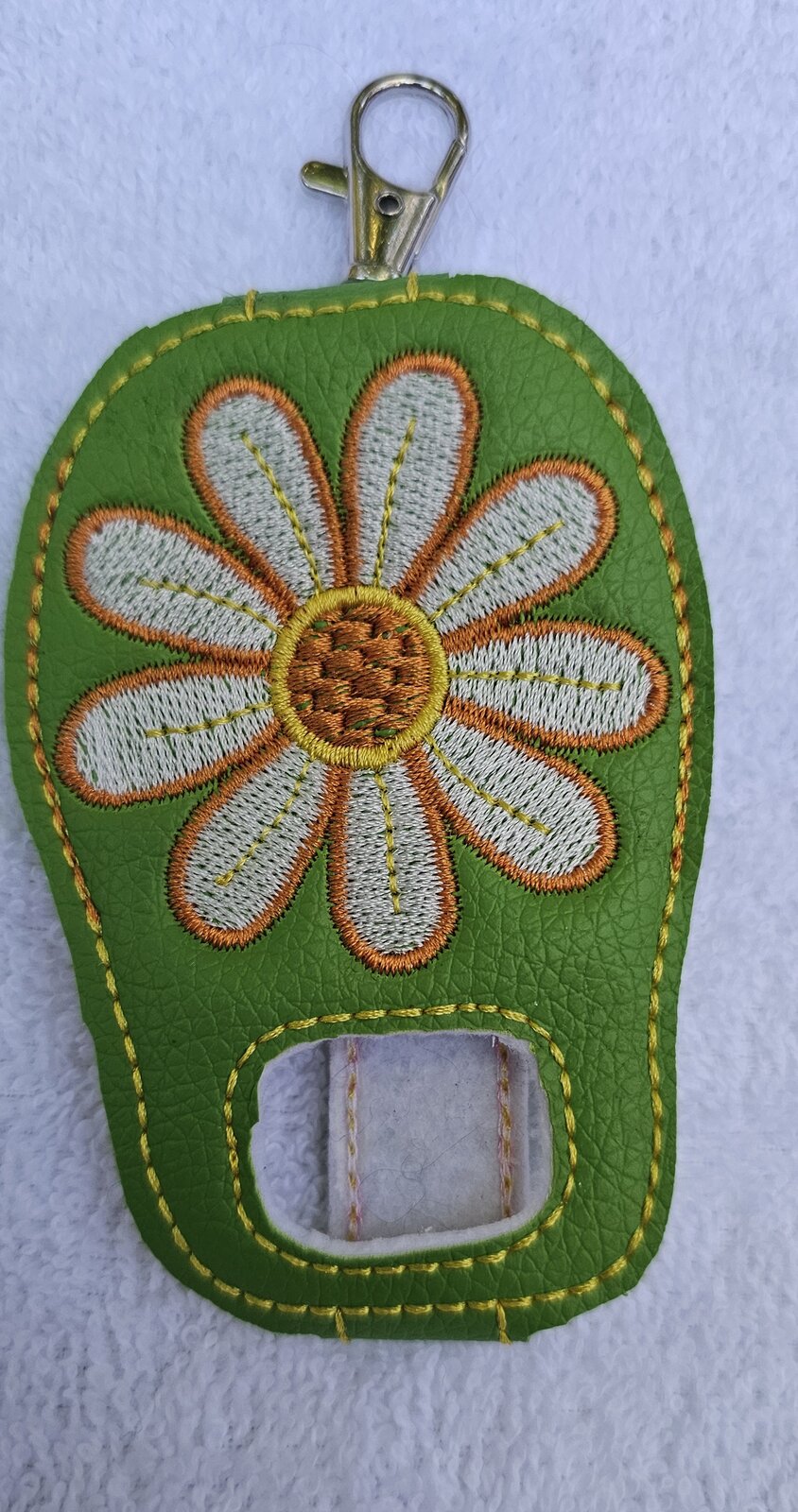 Green embroidered inhaler holder with a white and orange daisy and a clip