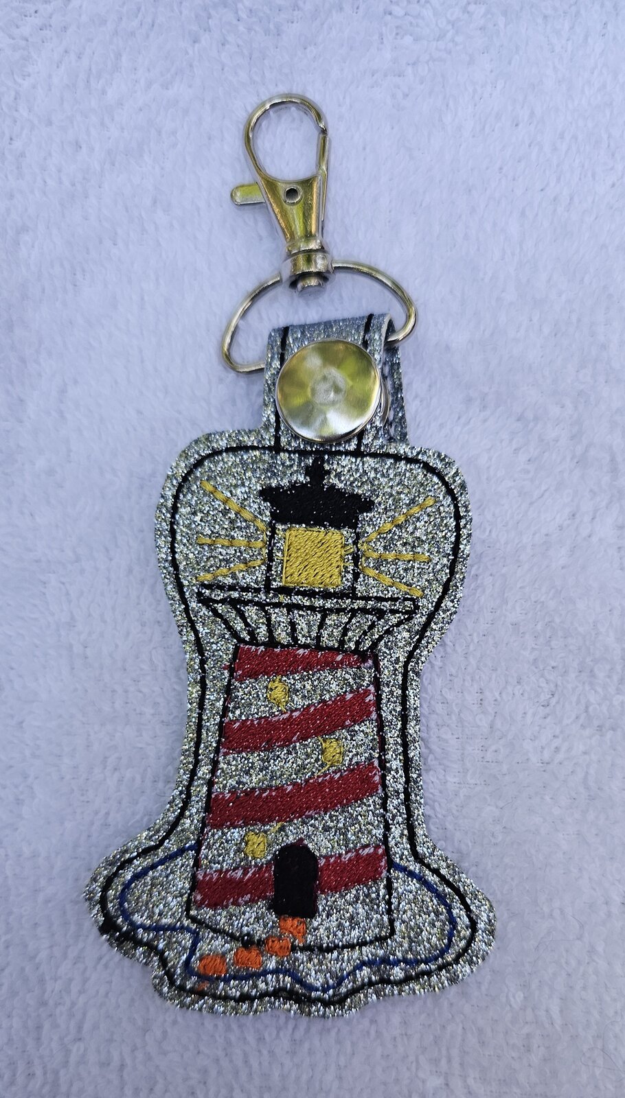 Silver sparkle key fob embroidered with a red and white striped lighthouse
