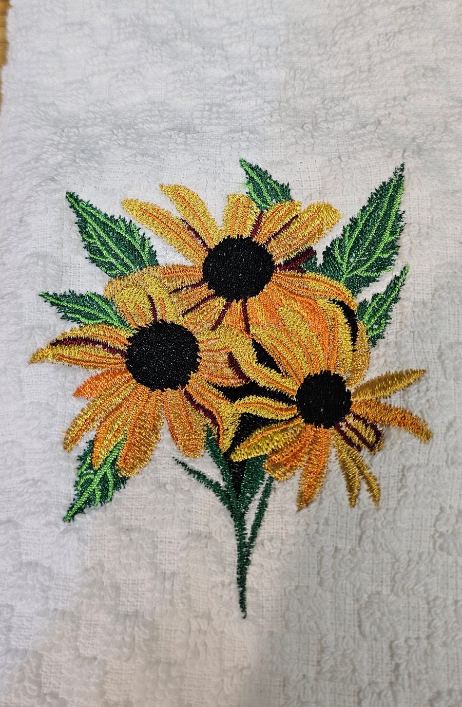 Black-eyed Susan flowers embroidered on a white kitchen towel