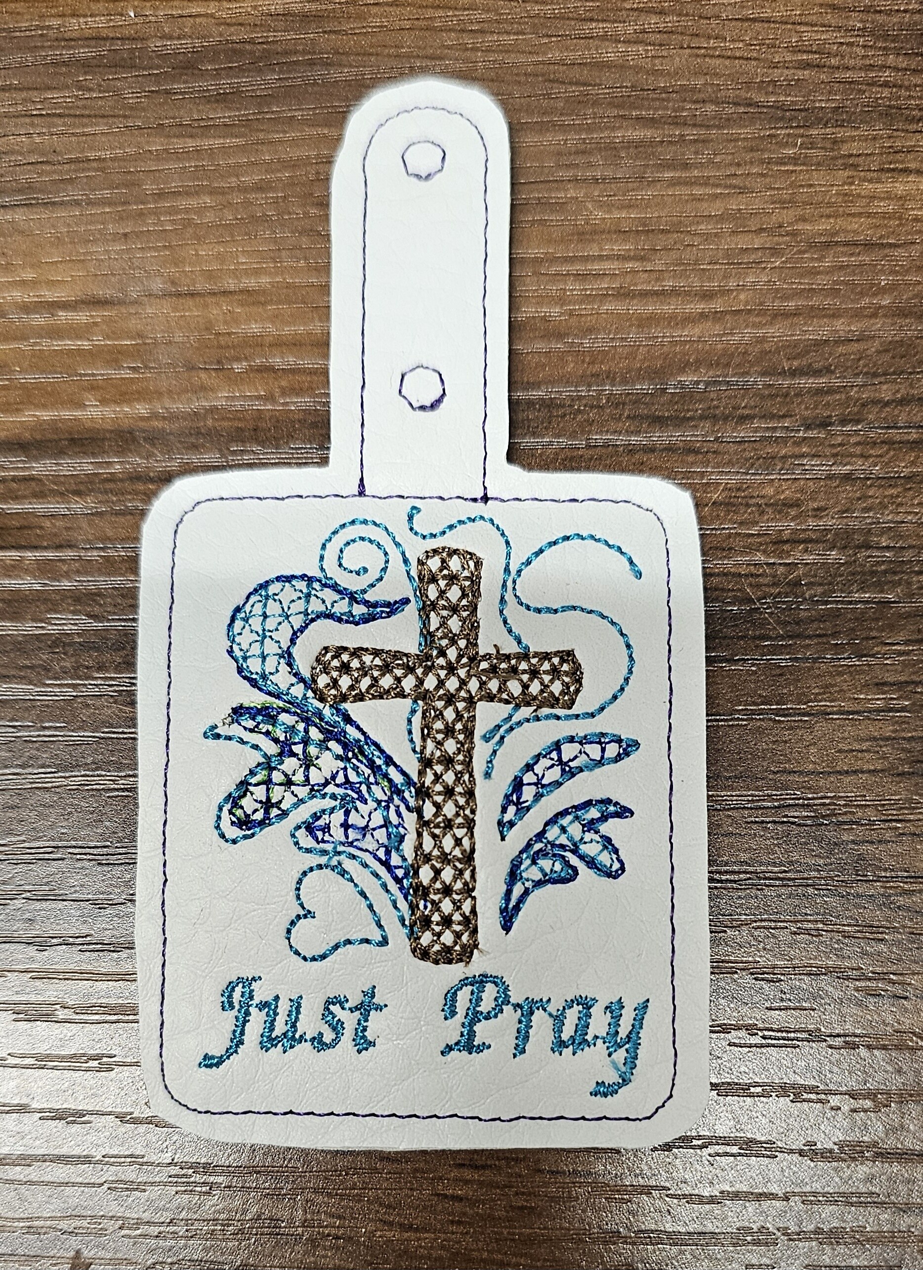 Embroidered key fob with a cross, lilies, and the words Just Pray